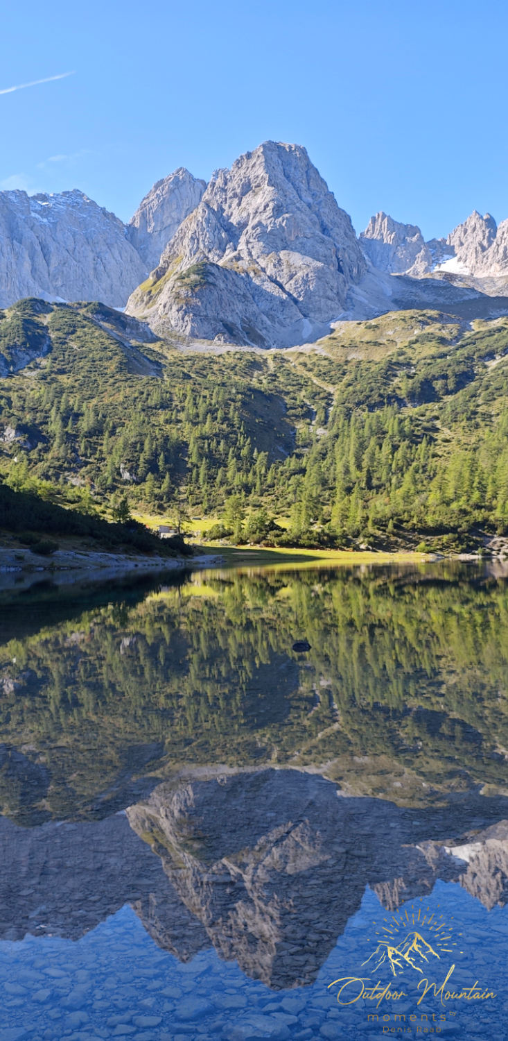 Berglandschaft mit spiegelndem Wasser und klar blauem Himmel.